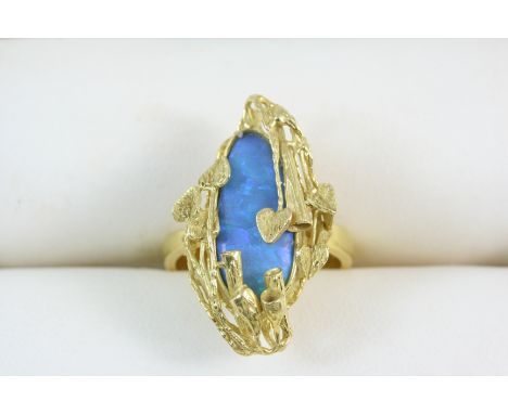 A BLACK OPAL AND GOLD RING the oval shaped opal is set within an elaborate floral 18ct. gold mount. Size N.