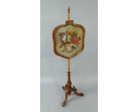 A Victorian walnut pole screen, with floral bead and woolwork tapestry, on a turned column and three pieced, scrolling cabrio