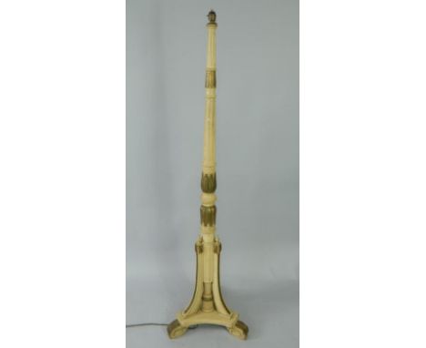An early 20thC cream and gilt painted standard lamp, with fluted and carved leaf decoration, raised on a triform base and scr
