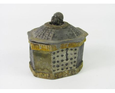 A lead tea caddy with a Blackamoor's head finial to the lid, of octagonal form with naively painted panels, 13cm x 9.5cm x 14