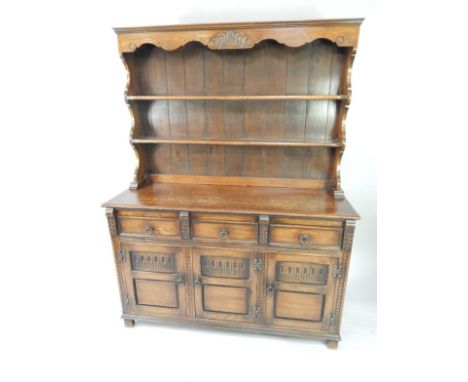 An oak dresser, the two shelf Delft rack over three frieze drawers and three carved panel doors, raised on block feet, 137cm 