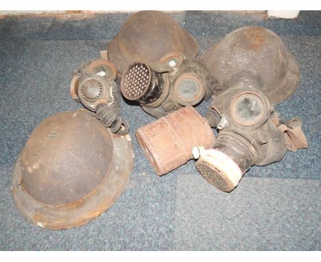 Three WWII British Army helmets, and three gas masks.
