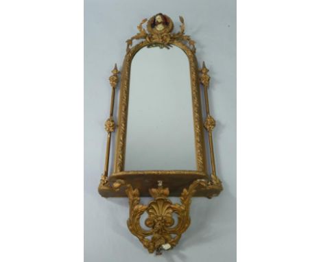 A French 19thC giltwood pier glass mirror, carved with a figural roundel and laurel wreath, domed glass flanked by floral col