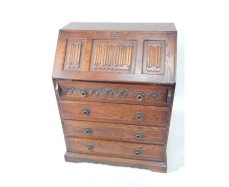An Old Charm oak bureau, the fall flap with linenfold carving enclosing cupboards and recesses, above four long graduated dra