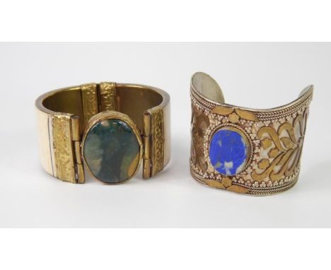 Two hardstone set bangles, comprising a green agate and brass bangle and a silver and blue stone set bangle. 