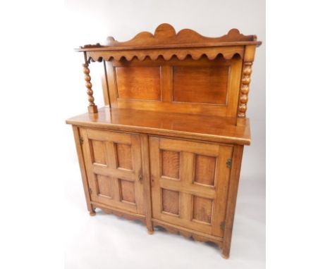 An Arts & Crafts style oak chiffonier, the galleried top raised on bobbin turned columns, above a pair of panelled doors, on 
