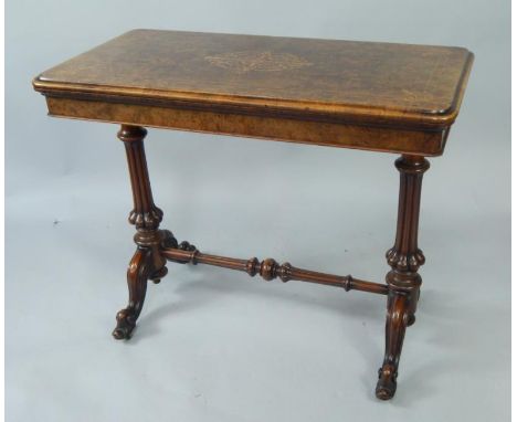 A Victorian walnut and boxwood inlaid fold over card table, the top with green baize inset, raised on fluted columns and cabr