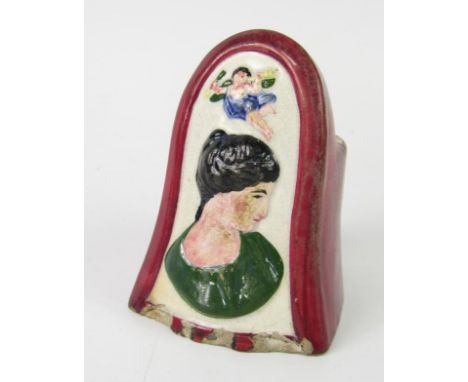 An early 19thC pearl ware sash window rest, decorated in relief with a female bust profile beneath Cupid, 11.5cm high.