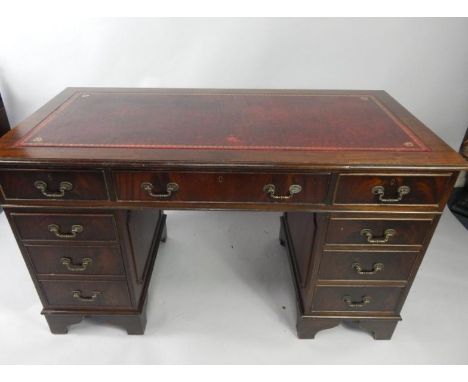 A mahogany twin pedestal desk, with a tooled red leather top, one long and eight short drawers, raised on bracket feet, 136.5