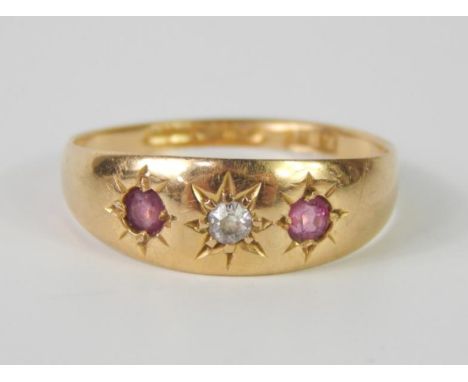 An 18ct gold diamond and ruby three stone ring, in a rub over star setting, size O, 2.8g. 