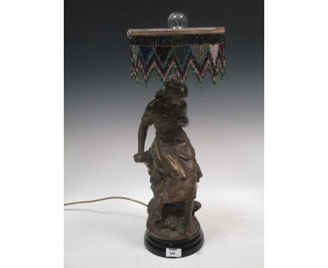 After Auguste Moreau, a bronzed spelter figural table lamp with bead work shade