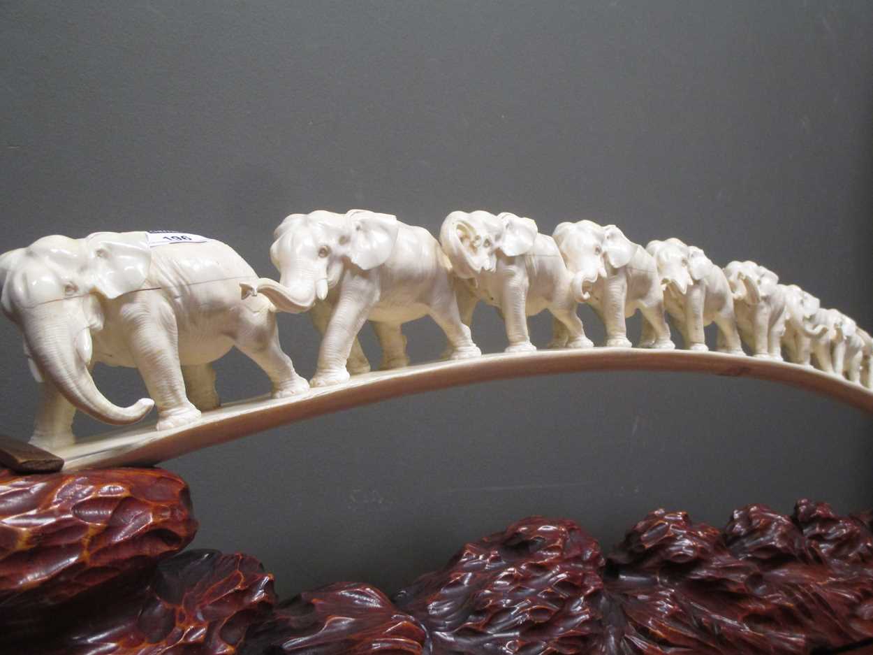 An ivory elephant tusk carved with twelve graduated elephants on a