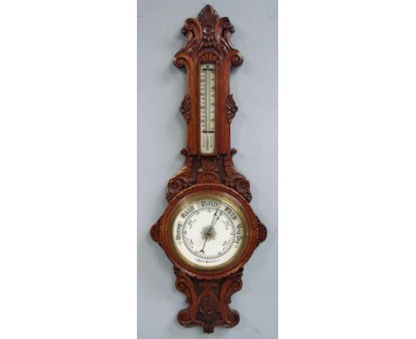 An early 20th century oak cased Aneroid Barometer, the banjo shaped frame carved with leaves and scrolls, mounted to the neck
