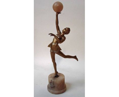 An Art Deco bronze patinated spelter figural model of a female dancer in typical costume, holding aloft an onyx ball, set on 