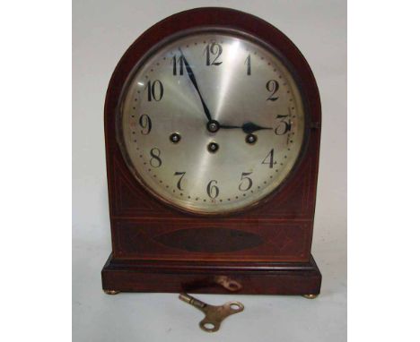 An Edwardian mahogany and inlaid cased Mantel Clock of arch top form set on shallow bun feet, the circular silvered dial with