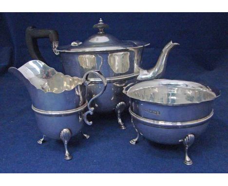 A George V silver three-piece tea service by Lee and Wigfull, of banded U form with flared shaped edges set on three hoof fee