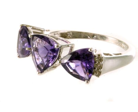 A 10K white gold and amethyst three stone ring, the three triangular cut amethysts flanked by three small clear stones, size 