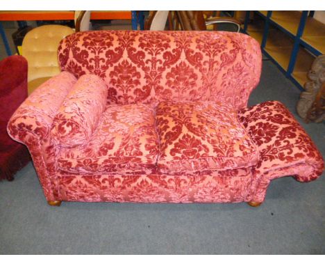 A 1920s drop arm Chesterfield sofa, finished in red brocade, and supported on bun feet with later casters 150cm W