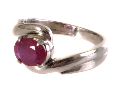 A white metal crossover dress ring, having an oval red cut stone, similar to a ruby, in mount marked 18k