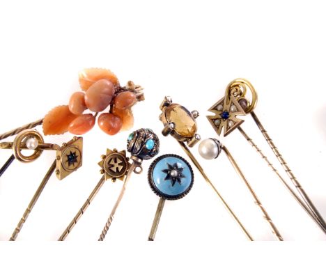 A group of ten yellow metal stick pins, including a cultured pearl example, a coral, gem set and more (10)