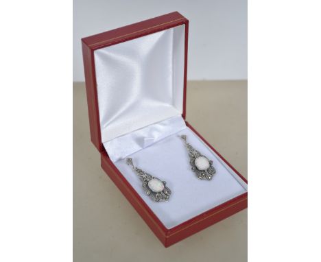 A pair of Art Deco style earrings set with a central opal and marcasite, cased. Total weight 6.5g. Measures 5cm drop.