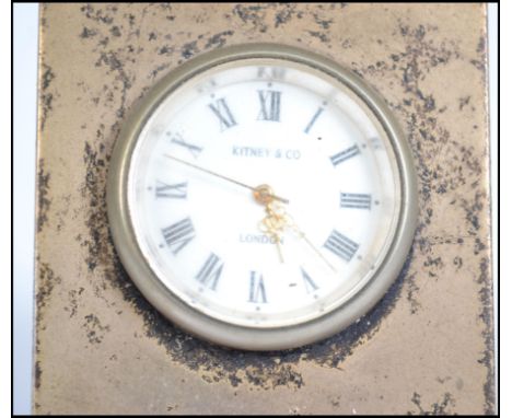 A small easel backed silver hallmarked clock. Enamel face with Roman numeral chapter ring. Retailer's stamp to the face for K