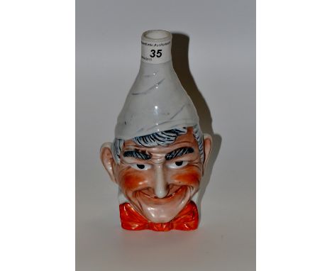 A Saxe Novelty mask vase, in relief with a comical man, wearing a red bow tie, wearing a tall pointed hat, 20cm high, printed