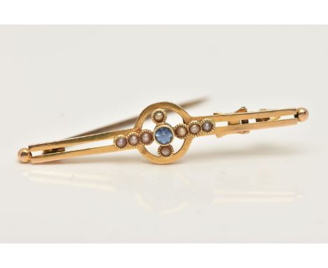 A YELLOW METAL GEM SET BROOCH, set with a central small light blue circular cut sapphire milgrain collet set, within a surrou