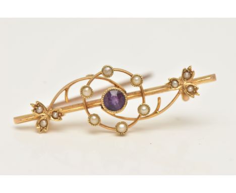 AN EARLY 20TH CENTURY BAR BROOCH, a yellow metal brooch principally set with a circular cut amethyst with a surround of six s