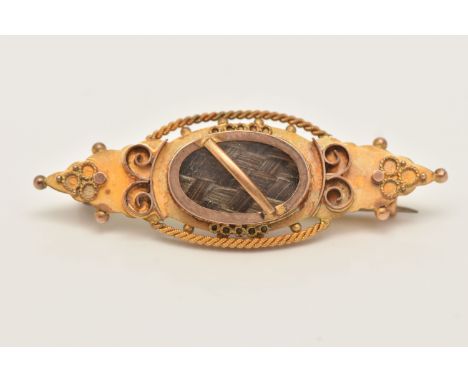 A 9CT GOLD HAIR PIECE BROOCH, set with a central oval panel with brown woven hair, beneath a glazed panel, to the scroll deta