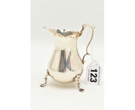 AN EARLY 20TH CENTURY SILVER MILK JUG, polished form with wavy rim, fitted with a scrolling handle and raised on three cabrio