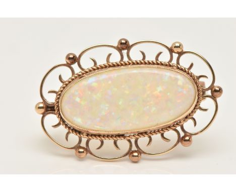 A 9CT GOLD AND SYNTHETIC OPAL BROOCH, an oval synthetic opal, collet set with open work scrolling detail, approximate length 