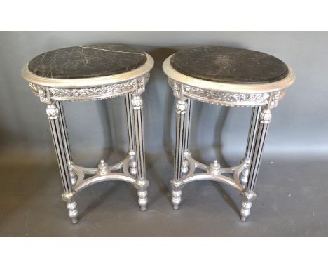 A Pair of French Style Silvered Oval Lamp Tables, the marble tops above a carved frieze raised upon turned reeded legs with c