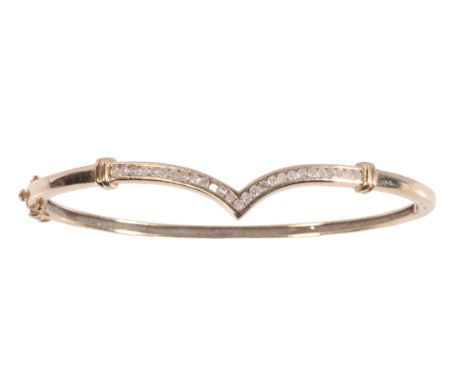 A DIAMOND SET GOLD BANGLE twenty-six rub-over set diamonds, (one diamond missing) of curved V form, on a 9ct yellow gold hing