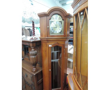 A modern yew wood effect longcase clock of corner design having glass trunk