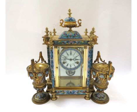 An early 20th Century highly decorative stirking mantel clock in brass/glazed architectural case with champlevé enamel detail