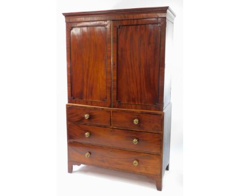 A George IV mahogany linen press, with ebony line inlay and cross banding, the outswept pediment over a pair of panelled door