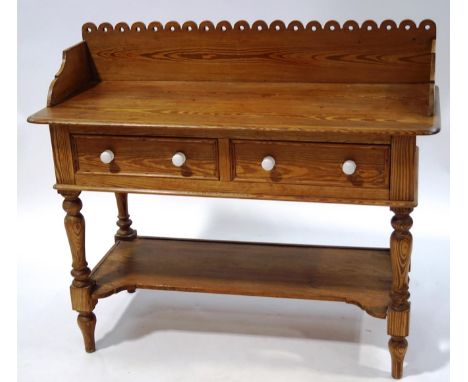 A Victorian pine wash stand  with raised pierced back above two drawers and ceramic handles above an under-tier with turned l