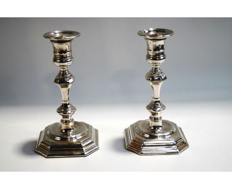 A pair of silver plated candlesticks, in the Georgian style, with square cut corner sunken bases, to a knopped and shouldered