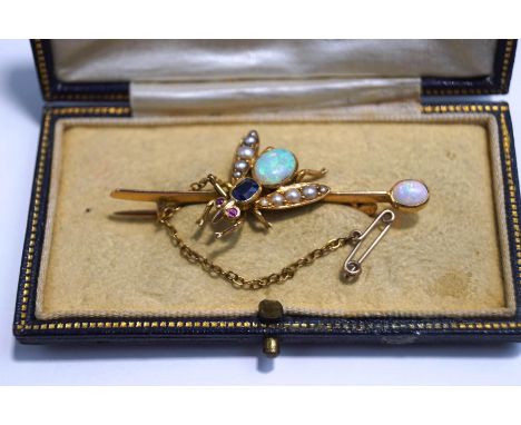 An Edwardian gem set bug bar brooch, the opal abdomen to a sapphire thorax, with ruby set eyes, the wings set with split pear