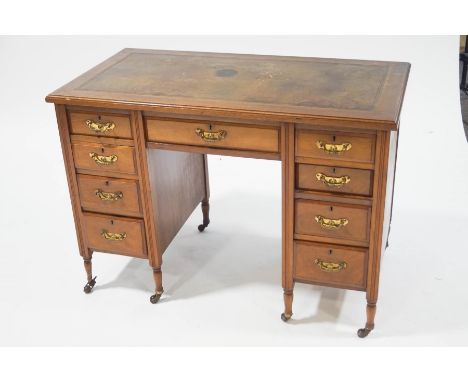 An Edwardian mahogany kneehole desk with leather inset top, three frieze drawers above three drawers to either side on turned