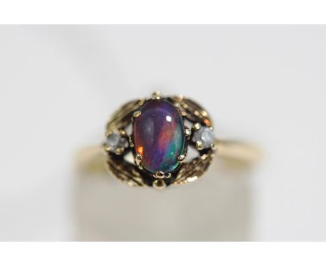 An opal triplet ring, stamped '9k', the cabochon between stone set shoulders, finger size M, 2.3 g gross