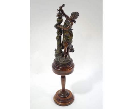After Moreau, a large spelter figure of a French maiden, standing next to a column, upon a turned wood stand with plaque insc