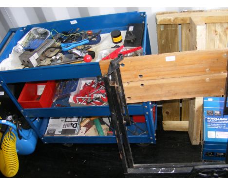 A blue metal tool trolley with a selection of tools and work bench