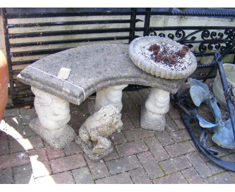 A concrete curved garden bench on three squirrel form plinths, together with a lion statue and bird bath top