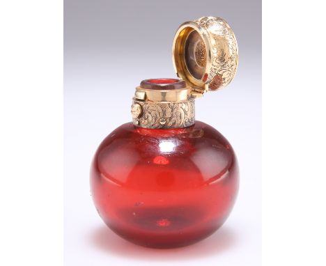 A VICTORIAN GOLD-MOUNTED RUBY GLASS SCENT BOTTLE, the spherical body with scroll and foliate engraved unmarked gold sprung ca