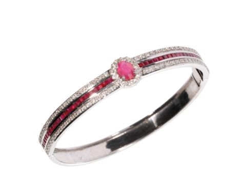 RUBY AND DIAMOND HINGED BANGLE, the centre ruby and diamond cluster, flanked either side with princess-cut rubies and round-c