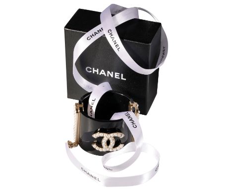 CHANEL CUFF FASHIONED IN BLACK LUCITE, WITH CENTRAL CC LOGO IN PEARL, with goldtone and pearl clasp detail, introduced in 201