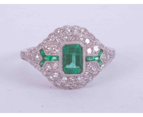 A platinum Art Deco style ring set central emerald cut emerald, approx. 0.55 carats surrounded by approx. 0.44 carats of roun