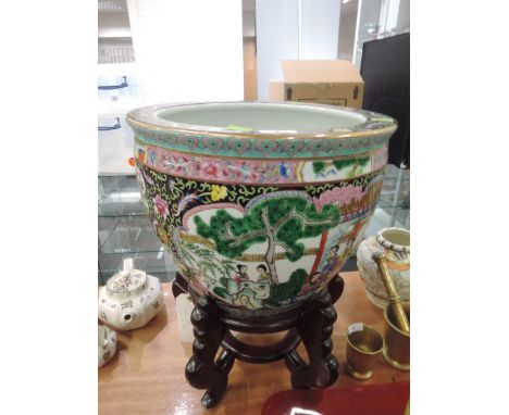 A ceramic oriental fish bowl with painted decoration and wooden stand